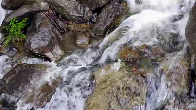 水在石头上流动。小水滴落在岩石上。水在石头间流动视频素材