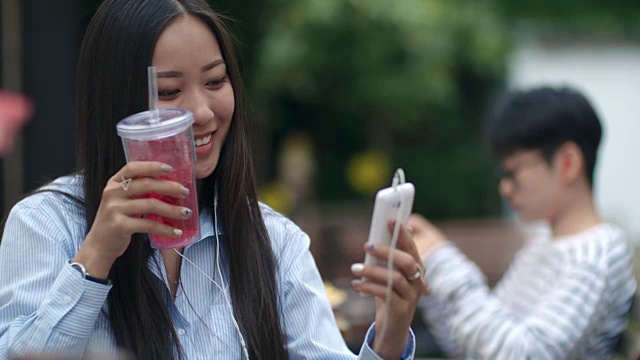 亚洲女性在户外咖啡馆用智能手机视频通话视频素材