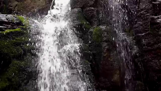 水流在岩石山上冲刷着长满青苔的石头。森林中的水流视频素材