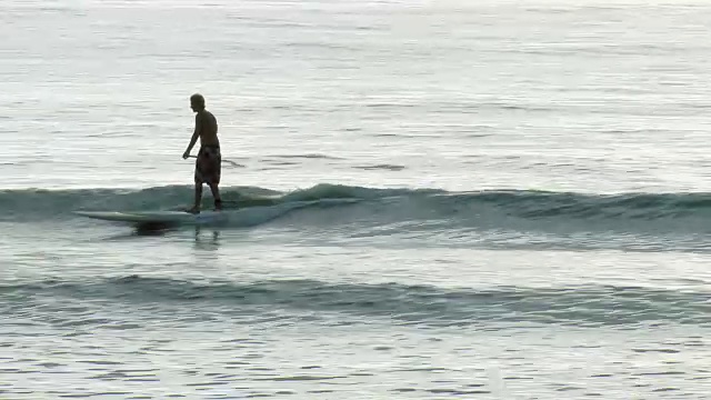 一个年轻人在冲浪板上冲浪视频素材