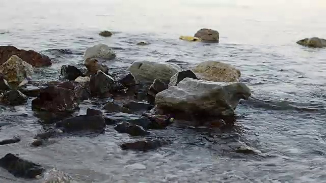 小波浪在白色沙滩岸边的岩石上的特写视频素材