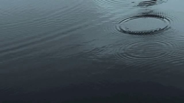 在雨季，近距离拍摄的雨滴落到河面的深色调，4K Dci分辨率视频素材