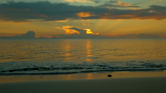 慢镜头:夕阳西下，波涛汹涌的海浪冲刷着宁静的沙滩。视频素材