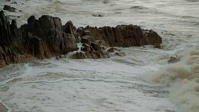 在雨天海浪拍打着岩石。视频素材