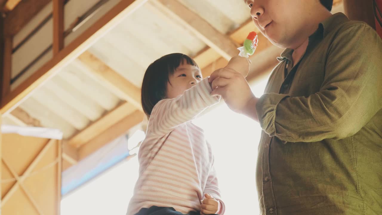 亚洲父亲和女儿分享一些冰淇淋，当他们享受吃快乐的情绪视频素材