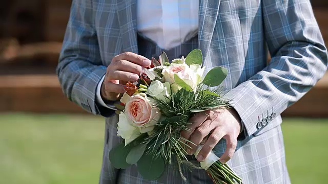 婚礼花束与美丽的鲜花在新郎的手中视频素材