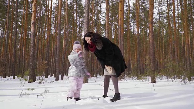 一名年轻女子和她的女儿站在冬天的森林里，向镜头挥手视频素材