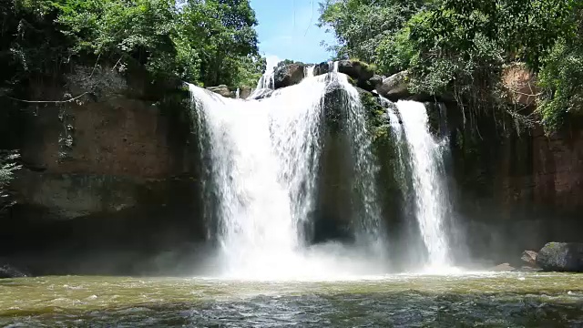 瀑布和水花在山上和郁郁葱葱的叶树视频素材