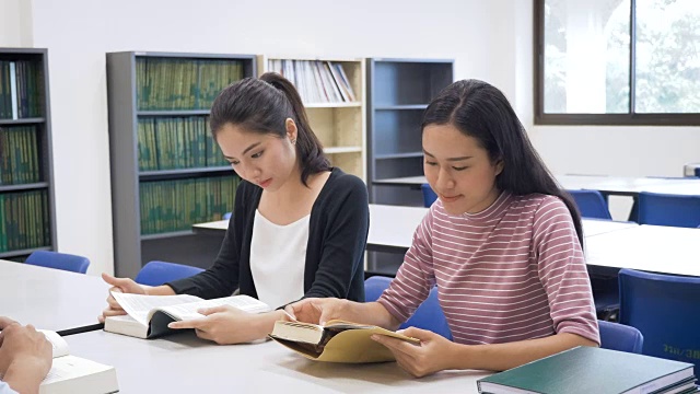 一群年轻的亚洲学生带着书在大学图书馆做研究，学习教育和学校理念视频素材