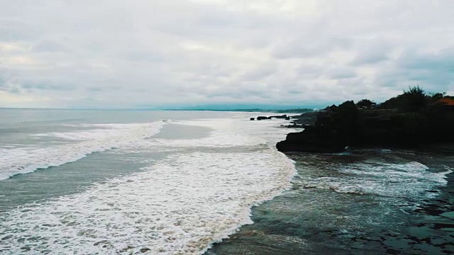 在一个阴天，海浪一浪一浪地涌向热带岛屿的海岸视频素材