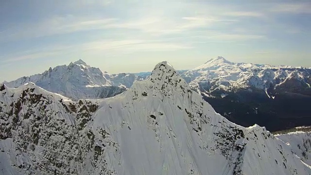 三角形的陡峭岩石的山峰空中飞行近距离看雪山的北方喀斯喀特山和贝克山自然冬季揭示背后的北方喀斯喀特山视频素材