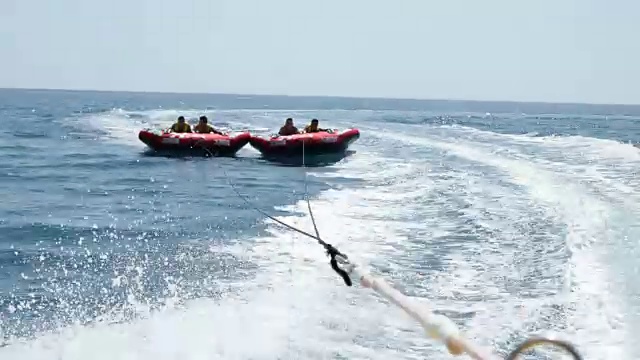 夏天的乐趣。四个朋友在海上享受充气管道之旅视频素材