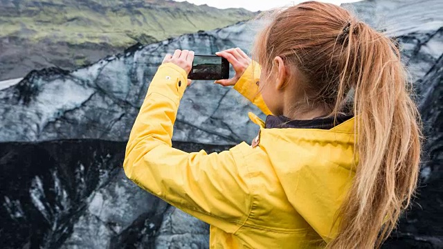 一名妇女正在拍摄被火山灰覆盖的冰川视频素材