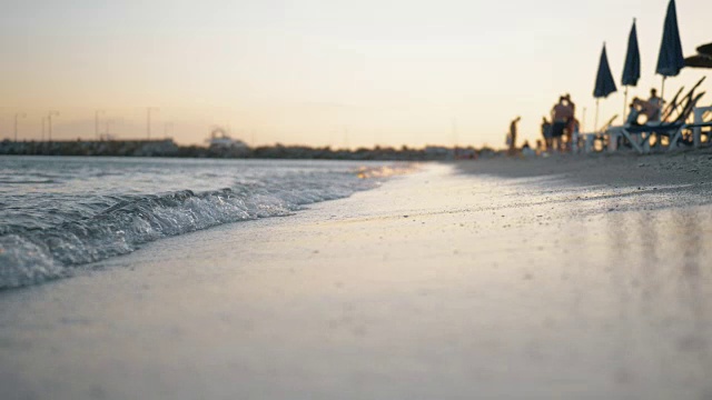 日落时海浪冲刷着度假胜地的海岸视频素材