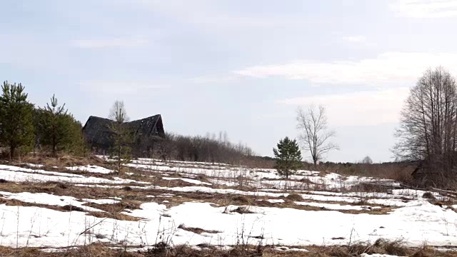 被遗弃和摧毁的俄罗斯村庄小屋分别矗立在雪地里，春天的时候。视频下载