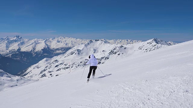 女子在山上以职业滑雪方式滑下斜坡视频素材