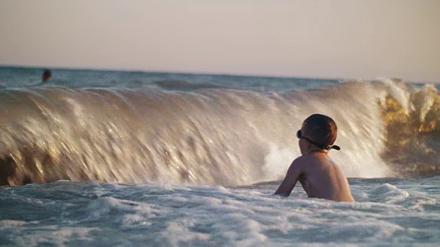 海浪打在孩子身上，溅了他一身水花视频素材