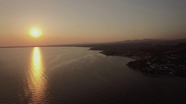 海边和海边的小镇，日落时，空中。希腊特里科尔福海滩的远景视频素材