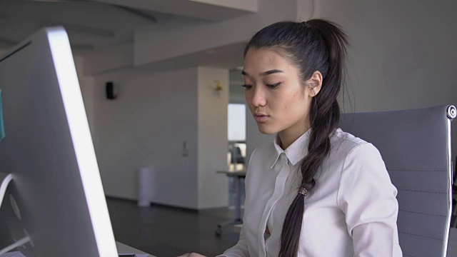 肖像美丽的商业女人是工作，坐在桌子与电脑在金融公司，看着显示器，打字文本，触摸脸。FullHD视频素材