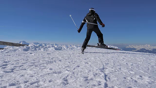 在雪山山顶的滑雪场，男子在斜坡上滑雪并快速转弯视频素材