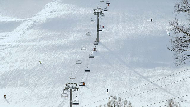 人们在冬季滑雪场的雪坡上滑雪和滑板。雪山上的滑雪电梯。冬季滑雪胜地的活动视频素材