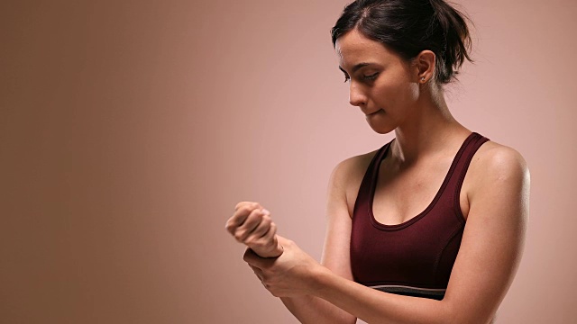 MS Young woman holding her painful wrist and rotation against pink background /新德里，德里，印度视频素材