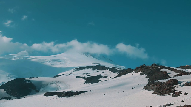 云朵在白雪皑皑的山顶上飞翔视频素材