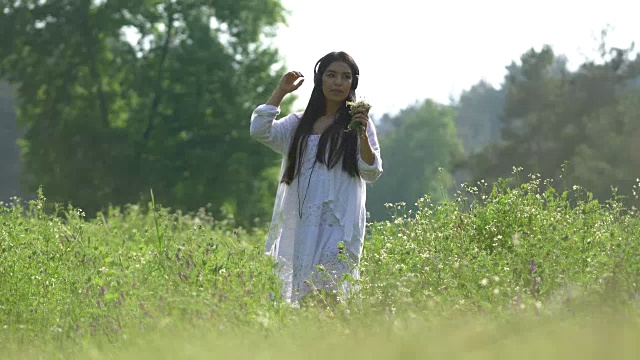 美丽的年轻女子在大自然中听音乐的肖像视频素材