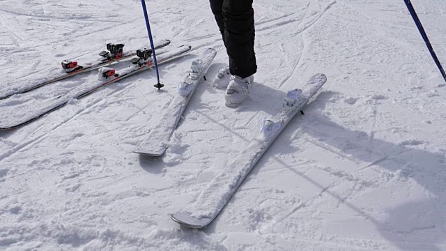 一个滑雪者穿着白色滑雪靴穿上他的下坡滑雪板视频素材