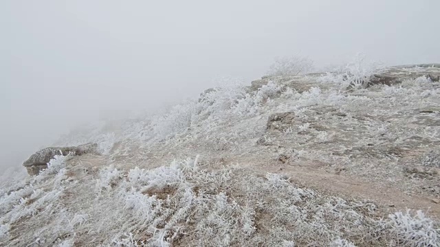 在石质山坡上的运动。岩石和草地上覆盖着白霜视频素材