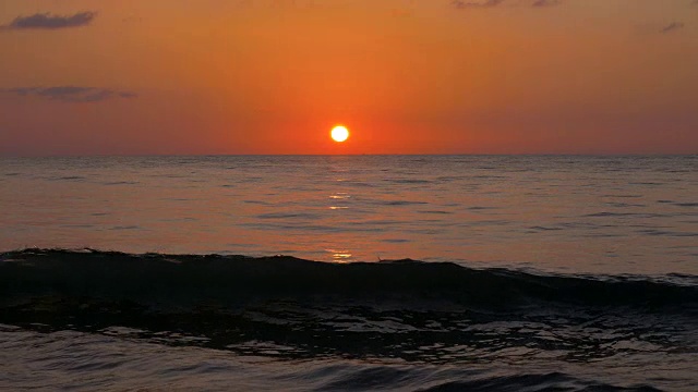 海面上的日落。阳光和橙色的天空反射在海浪上。慢动作镜头。4 k, UHD视频素材