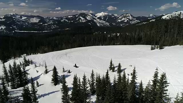 在喀斯喀特山脉的背景下骑雪上汽车天线视频素材