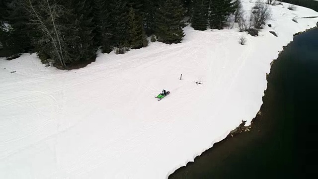 骑着雪地摩托在雪公园湖边飞驰视频素材