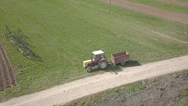 拖拉机和汽车一起在田间道路上行驶。视频素材