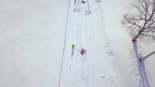 人们在冬季滑雪场的雪坡上乘坐滑雪缆车。滑雪电梯在雪山运输滑雪者和滑雪板无人机视图视频素材