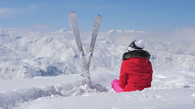 一位美丽的滑雪者坐在雪地里看向别处视频素材