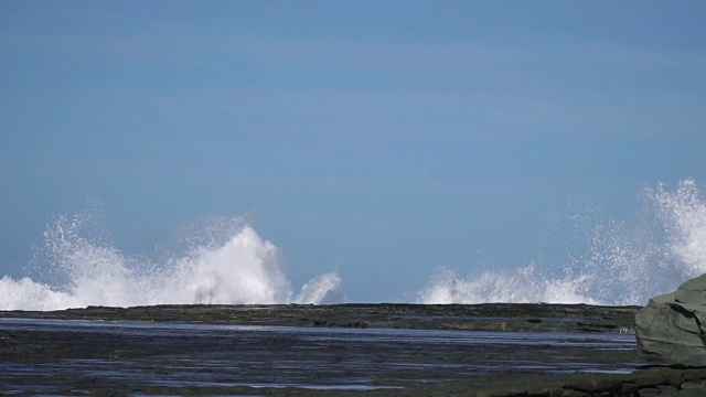 慢镜头海浪撞击海岸岩石，溅起巨大水花视频素材