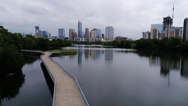 在滨河行人桥上的城镇湖空的不祥的一天，无人机的视图与市中心天际线城市景观桥的右上方视频素材