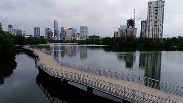 在桥上与一群皮划艇沿着城镇湖与奥斯汀，德克萨斯州天际线城市景观的背景完美的倒影在水面上视频素材