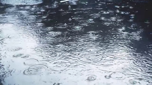 雨点缓慢地落在人行道上。视频素材