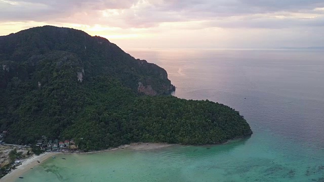 鸟瞰图:鲜艳的橙色日出隐藏在保护村庄的石灰岩山丘后面。视频素材