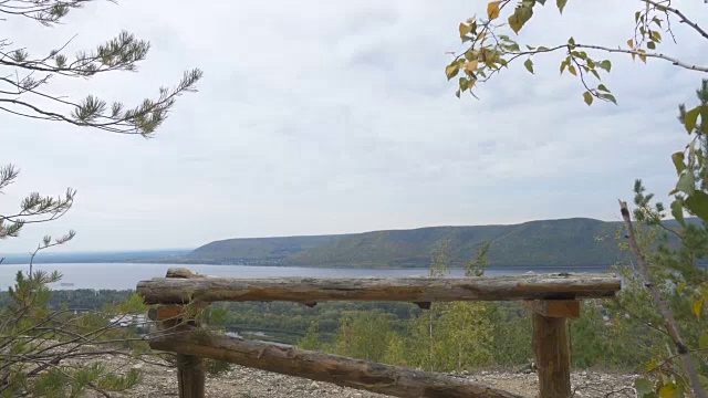 山中悬崖边的木头长凳。秋天的风景。山谷中的河流，地平线上是群山。视频素材