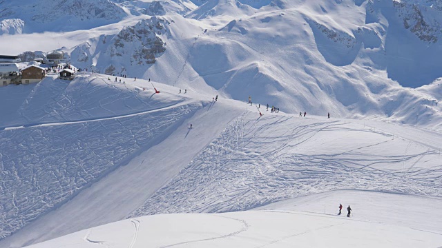 阳光明媚的一天在雪山滑雪场，许多滑雪者在斜坡上视频素材