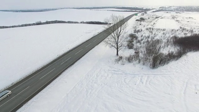 空中拍摄的卡车和汽车行驶在雪地里的冬季道路上。视频素材