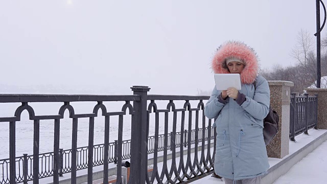 一名年轻女子在冬天的户外使用数码平板电脑视频素材