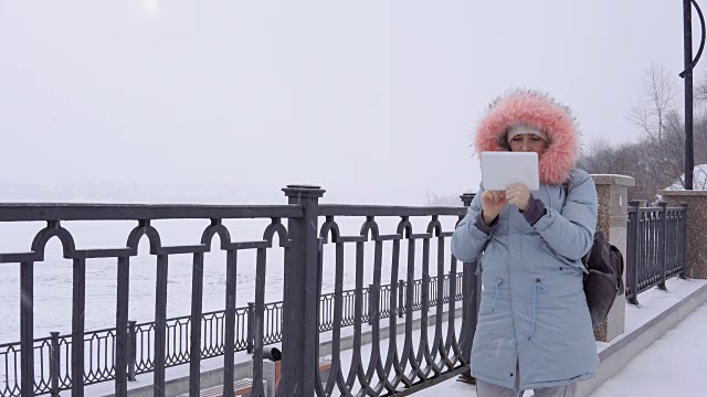 一名年轻女子在冬天的户外使用数码平板电脑视频素材