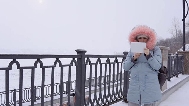 一名年轻女子在冬天的户外使用数码平板电脑视频素材