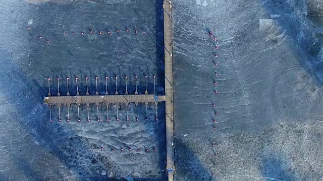 阳光明媚的冬日，冰冻湖湾和码头的航拍视频素材