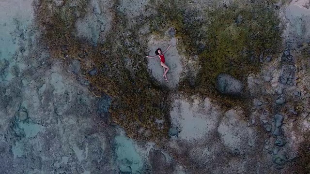 美丽的年轻女子躺在巴厘岛海滩的沙滩上视频素材