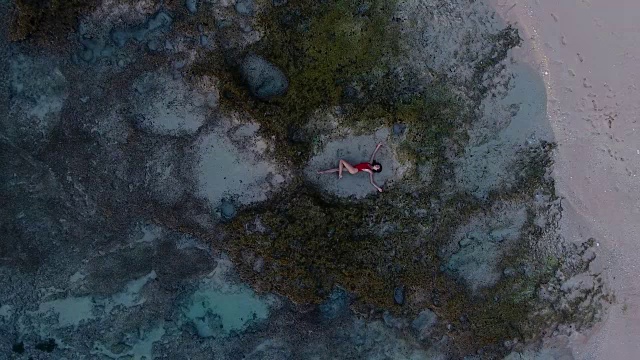 美丽的年轻女子躺在巴厘岛海滩的沙滩上视频素材